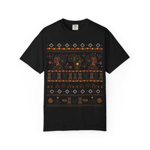 May include: A black short-sleeve t-shirt featuring a graphic print with two profiles of individuals with afro hairstyles, a map of Africa, and horizontal bands of geometric patterns in red, green, yellow, and white colors across the chest area.