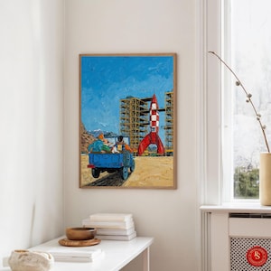 May include: A framed painting depicts a blue truck with passengers, driving towards a red and white rocket. The background features a blue sky, construction scaffolding, and a sandy landscape. The artwork has a textured, impressionistic style.
