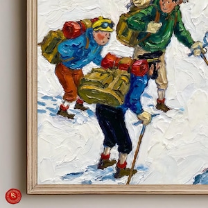 May include: Oil painting of three people hiking in the snow, each with a backpack. The hikers wear colorful jackets, pants, and hats. The painting is framed in a light-colored wooden frame. The painting has a textured, impressionistic style.