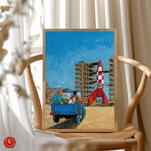 May include: A framed print depicting a scene with a red and white rocket, a blue truck, and figures. The artwork has a blue sky background and is set against a construction site. The print is displayed on a wooden chair.