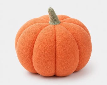 May include: A plush pumpkin decoration featuring a vibrant orange, textured fabric body with deep vertical ridges and a short, sage green stem at the top. The soft, rounded object mimics the shape of a gourd with a fuzzy, tactile surface.