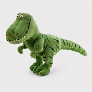 May include: A plush Tyrannosaurus Rex toy in a vibrant green color with darker green stripes along its back and tail. The dinosaur features a large head, white embroidered teeth, two small arms, and two sturdy legs with visible stitched details.