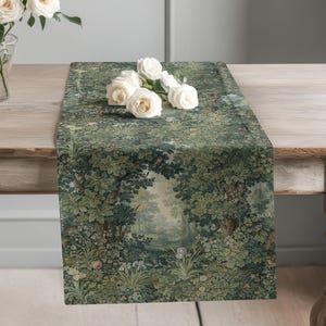 May include: A rectangular table runner featuring a detailed woven tapestry design of a lush forest landscape with dense green trees, foliage, and small flowers. A cluster of white roses is placed on top of the fabric surface.