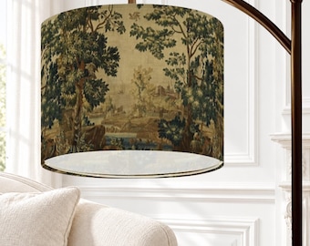 May include: A floor lamp with a dark bronze arched metal stand and a cylindrical fabric lampshade featuring a detailed tapestry-style print of a landscape with green trees, rocky terrain, and a distant building under a pale sky.