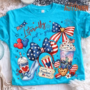 May include: A turquoise t-shirt with a patriotic design featuring a bow, Mickey Mouse ears, and a high heel. The shirt includes the text "Literally just a girl" and other American-themed graphics.