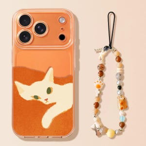 Könnte beinhalten: Transparente orangefarbene Handyhülle mit einer weißen Katzenillustration und einem Perlenanhänger. Die Hülle hat ein Katzendesign auf orangefarbenem Hintergrund. Der Anhänger hat verschiedene Perlen.