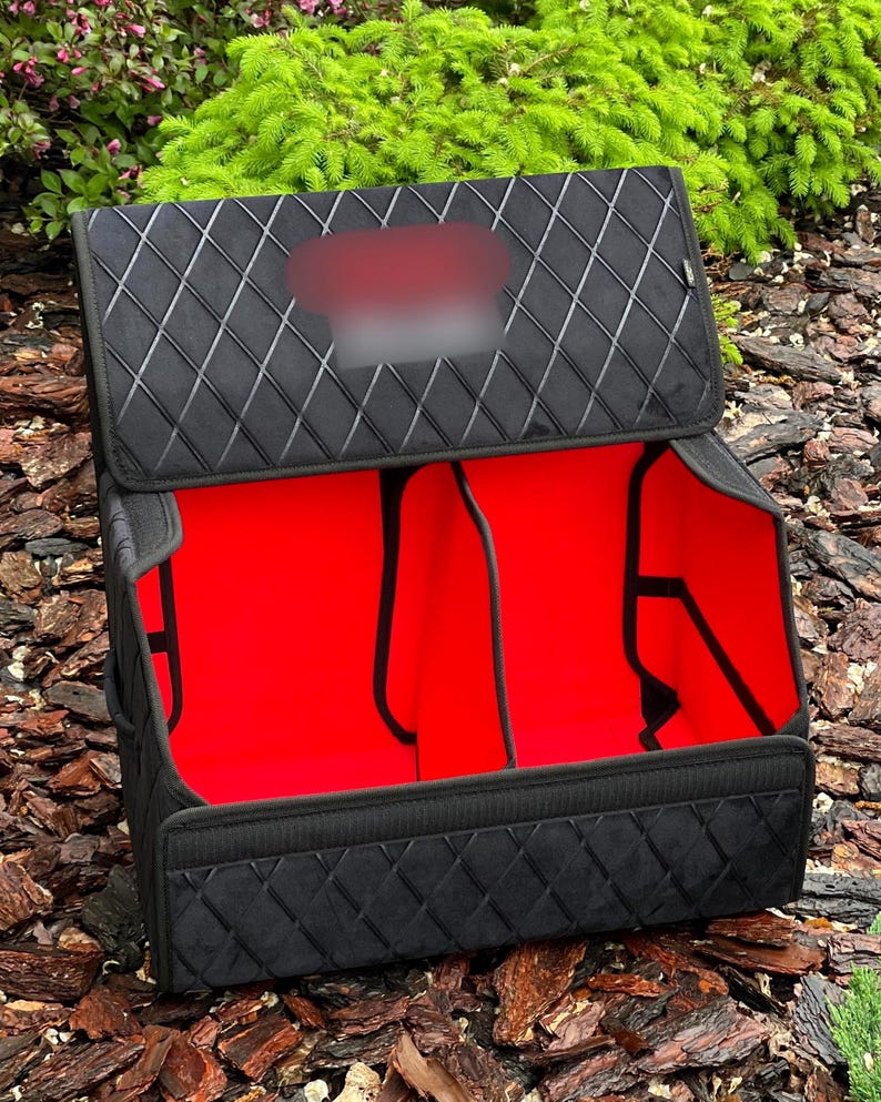 May include: Black car trunk organizer with a quilted pattern on the exterior. The interior is bright red and divided into compartments. The organizer is open, revealing the interior and the dividers.