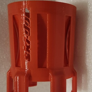 Könnte beinhalten: Ein leuchtend orangefarbenes zylindrisches Objekt mit rechteckigen Aussparungen und dem Text "Ski-Doo" auf der Seite. Das Objekt hat einen Sockel mit vier kleinen Beinen. Der Artikel scheint aus Kunststoff zu sein.