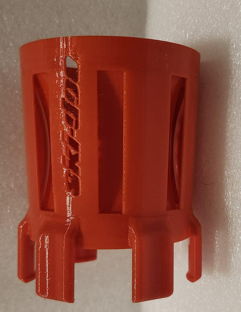 Puede incluir: Un objeto cil&iacute;ndrico de color naranja brillante con recortes rectangulares y el texto "Ski-Doo" en relieve en el lateral. El objeto tiene una base con cuatro patas peque&ntilde;as. El art&iacute;culo parece ser de pl&aacute;stico.