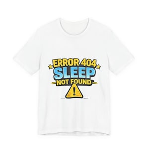 Op de afbeelding: Wit T-shirt met de tekst "ERROR 404 SLEEP NOT FOUND" in blauw, geel en zwart. Het ontwerp bevat een geel waarschuwingsbord. Een casual kledingstuk.
