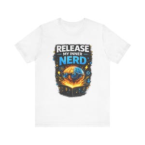 May include: White t-shirt with a graphic design featuring a brain wearing glasses, split into two halves, one brown and one blue. The text "RELEASE MY INNER NERD" is above the brain image, with a black border and yellow and blue accents.