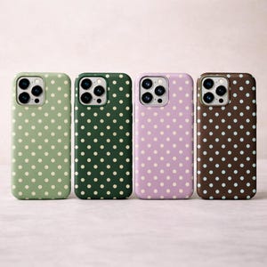 May include: Four phone cases in a row, each with a different color and polka dot pattern. The colors are green, dark green, lavender, and brown. The polka dots are white or light blue.