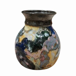 May include: A small ceramic vase with a rounded body and a flared rim. The surface features a multi-coloured glaze with swirling patterns of deep blue, forest green, soft pink, ochre yellow, and white, finished with a dark metallic rim.
