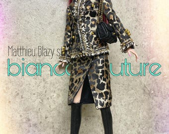 May include: A fashion doll with magenta hair wearing black sunglasses, a black and gold leopard print jacket with frayed edges and gold buttons, a matching knee-length skirt, a black quilted handbag, and black knee-high boots. Text reads Matthieu Blazy style biancocouture.