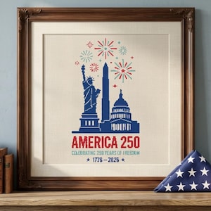 May include: Framed artwork celebrating 250 years of American freedom. The design features the Statue of Liberty, the Washington Monument, and the Capitol Building in blue, with red text that reads "AMERICA 250". Fireworks and the years 1776-2026 are also included.
