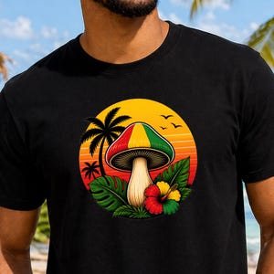 May include: Black crew neck t-shirt featuring a colorful mushroom graphic with a sunset background, palm trees, and tropical flowers. The design incorporates red, yellow, and green colors. The shirt is worn on a beach with a bar and ocean in the background.