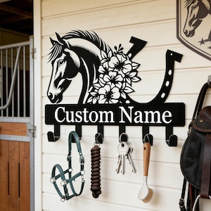 May include: Black metal horse head and horseshoe wall-mounted key and accessory holder. Features the text "Custom Name" and hooks for hanging items. Includes a horse halter, rope, keys, and brush.