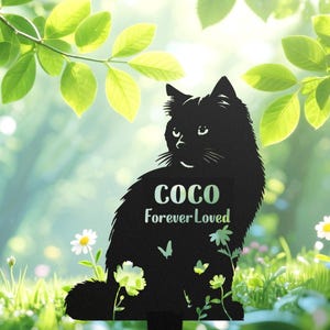 May include: A black metal cat silhouette garden stake with the name "COCO" and the words "Forever Loved" in a gradient green font. The stake features floral and butterfly cutouts, set against a blurred green and white background.