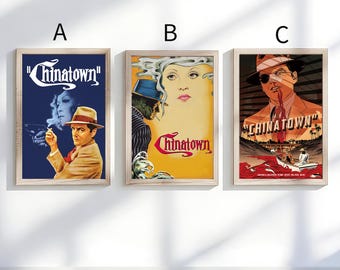 May include: Three framed movie posters for the film "Chinatown". Each poster features vintage artwork with a distinct color palette and imagery. The posters are in wooden frames and are displayed against a white wall.