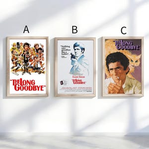 May include: Three framed movie posters for "The Long Goodbye" are displayed. The posters feature vintage artwork and text, with a variety of character illustrations and promotional images. The posters are in wooden frames.