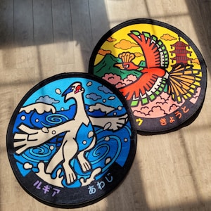 May include: Two circular rugs with vibrant illustrations. One depicts a white and blue creature in a blue and white water design, with Japanese text. The other rug shows a red bird against a yellow and orange backdrop, also with Japanese text.