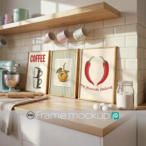 May include: A kitchen scene with framed art, mugs, and a stand mixer. The art includes a coffee-themed print, a donut illustration, and a chili pepper design with the text "my favorite feeling". A jar of flour and eggs are on the counter.