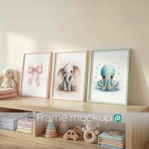 May include: Three framed art prints featuring a pink bow, a baby elephant, and a blue octopus. The frames have pastel colors and are displayed on a wooden shelf with children's toys. The overall theme is nursery decor.