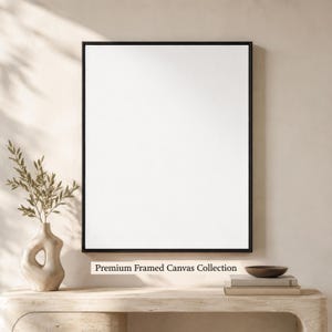 Puede incluir: Un lienzo blanco rectangular vertical en blanco encerrado en un marco negro fino. Debajo del marco, el texto Premium Framed Canvas Collection está impreso en una fuente serif oscura. El lienzo está colocado contra una pared de tonos neutros.