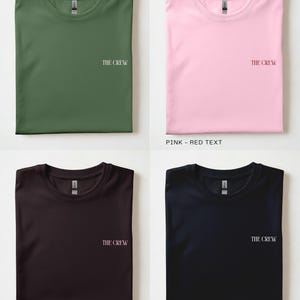 Puede incluir: Cuatro camisetas dobladas en diferentes colores: verde oliva, rosa, chocolate oscuro y negro. Cada camiseta tiene el texto "THE CREW" impreso. La camiseta rosa tiene texto rojo, la camiseta chocolate oscuro tiene texto rosado y la camiseta negra tiene texto blanco roto.
