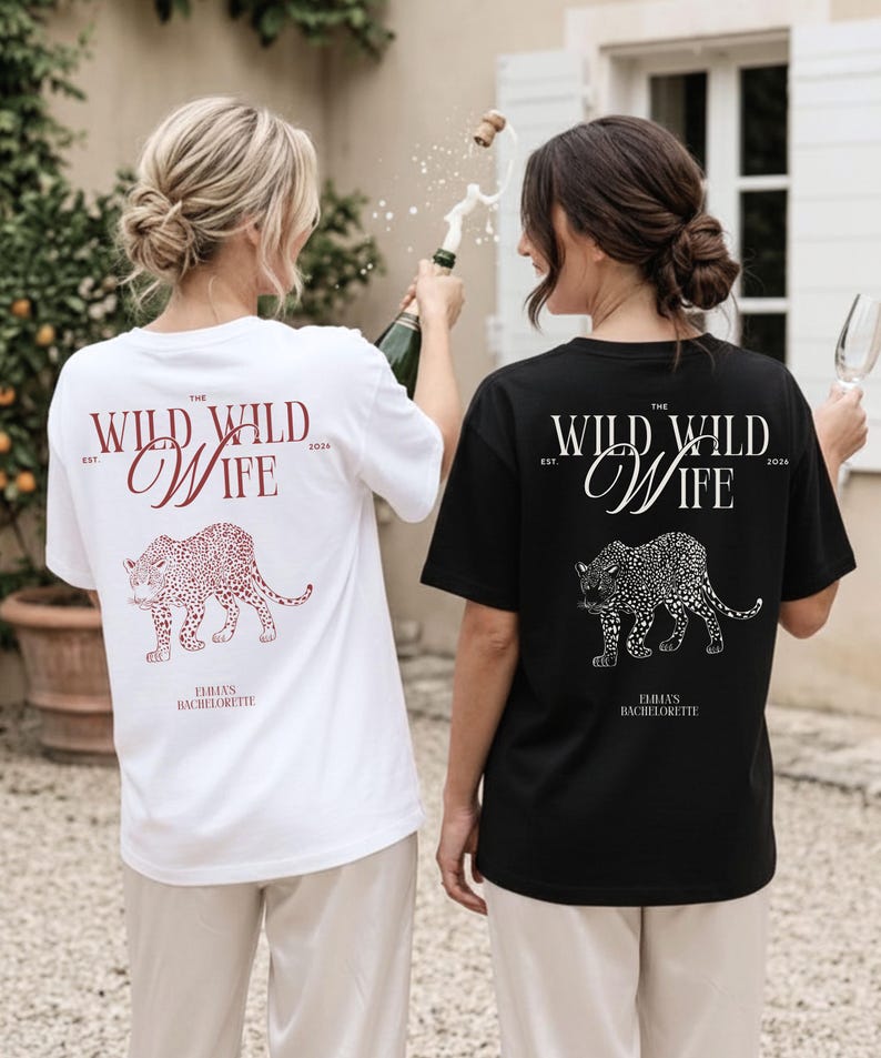 Puede incluir: Dos camisetas, una blanca y otra negra, con un dise&ntilde;o de leopardo y el texto "The Wild Wild Wife" y "Emma's Bachelorette". La camiseta blanca tiene texto burdeos, la camiseta negra tiene texto blanco.