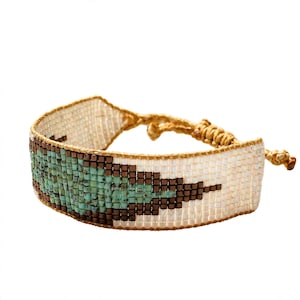Könnte beinhalten: Ein gewebtes Perlenarmband mit einem geometrischen Muster aus türkisfarbenen, dunkelbraunen und schillernd weißen Glasperlen. Das Armband ist mit einer beigen Kordel gefertigt und verfügt über einen verstellbaren Schiebeknotenverschluss.