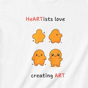 Könnte beinhalten: Ein weißes T-Shirt mit dem Text "HeARTists love" über vier orangefarbenen, klecksartigen Zeichentrickfiguren in verschiedenen Entwicklungsstadien, mit dem Text "creating ART" darunter in schwarzer und roter Schrift.