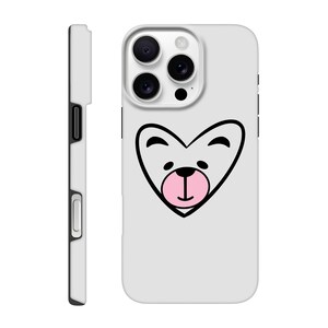 Puede incluir: Una funda de teléfono blanca con un diseño de cara de oso en forma de corazón negro y rosa. La funda tiene una vista lateral que muestra un botón negro y un recorte para la cámara. La cara del oso tiene contornos negros y una nariz rosa.