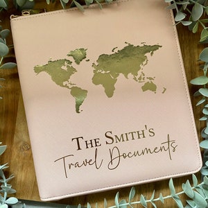 May include: A pink travel document holder with a gold world map design and the text "THE SMITH'S Travel Documents".