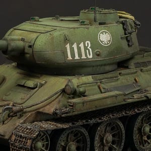Könnte beinhalten: Detailliertes Modell eines grünen Militärpanzers mit langem Lauf. Der Panzer hat sichtbare Ketten und Räder, und die Nummer "1113" ist auf den Turm gemalt. Das Modell steht vor einem dunklen Hintergrund.