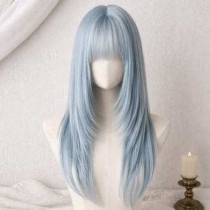Peut inclure: Une perruque longue et droite de couleur bleu clair avec une raie au milieu et une frange effilée. Les cheveux sont coiffés avec des pointes dégradées qui encadrent le visage, offrant un aspect lisse et soigné sur un mannequin neutre.