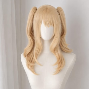 May include: A light blonde wig styled with two high pigtails and straight bangs. The hair features long, wavy ends that fall past the shoulders, displayed on a white mannequin head and torso to showcase the layered cut and soft colour.