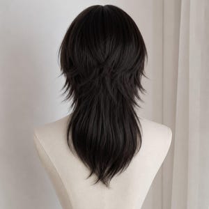 May include: A dark brown wig featuring a layered, shaggy cut with shorter, textured pieces at the crown and longer, tapered strands extending down the back. The hair is styled with a voluminous, feathered appearance and a soft, natural-looking finish.