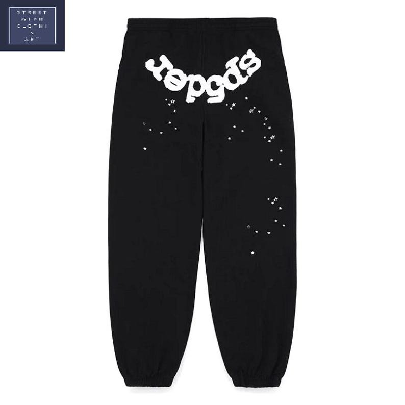 K&ouml;nnte beinhalten: Schwarze Jogginghose mit wei&szlig;em "Spider"-Schriftzug auf dem R&uuml;cken und einem Sternbild-Design. Die Jogginghose hat eine lockere Passform und einen Kordelzug in der Taille. Der Text und die Konstellation sind aus weichem, strukturiertem Material.