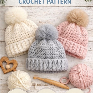 May include: Three crocheted baby beanies in cream, grey, and pink, each with a fluffy pom-pom. The image includes yarn, a crochet hook, and text that reads "Easy Baby Beanie Crochet Pattern" and "Sizes: 0-12 Months."