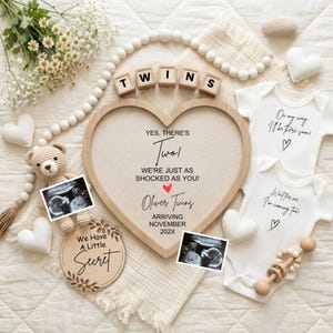 May include: A heart-shaped wooden frame with the text "YES, THERE'S TWO!" and "Oliver Twins ARRIVING NOVEMBER 202X". Includes baby clothes, ultrasound images, and wooden blocks spelling "TWINS".