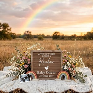 Könnte beinhalten: Eine Schwangerschaftsankündigung mit einem Regenbogen am Himmel. Eine braune Buchstaben-Tafel zeigt "Nach dem Sturm kommt ein Regenbogen" mit dem Namen "Baby Oliver" und dem Datum "Oktober 202X". Die Ankündigung ist von Blumen und zwei Regenbogen-Dekorationen umgeben.