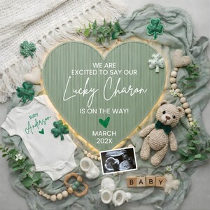 Puede incluir: Anuncio de bebé con un letrero verde en forma de corazón que dice "¡Estamos emocionados de decir que nuestro Lucky Charon está en camino!" Un body blanco con "Baby Anderson" está junto a un osito de peluche, una foto de ultrasonido y bloques de madera "BABY."
