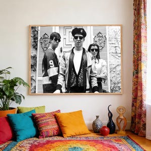May include: A black and white framed wall art print featuring three individuals wearing sunglasses standing in front of a door with the text Chez Quis. The central figure wears a beret and a jacket, while the others wear a jersey and a light top.