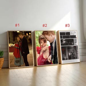 May include: Three framed movie posters leaning against a wall. The posters feature images from the films "About Time" and "Love Actually". The posters are in wooden frames and are displayed indoors.