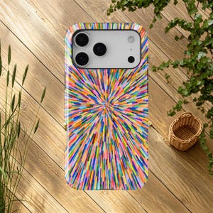 Pode incluir: Uma capa de smartphone com um padrão radial multicolorido e vibrante de linhas finas e alongadas em tons de azul, amarelo, rosa, verde e laranja, irradiando do centro para as bordas da capa retangular.