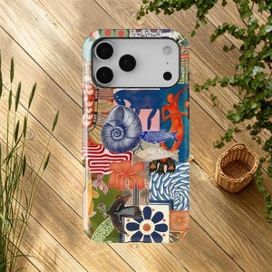 May include: A patterned phone case with a collage design featuring marine life and abstract shapes. The design includes a nautilus shell, fish, and floral elements in blue, orange, and green. The case is displayed on a wooden surface.