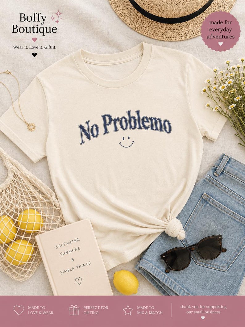 May include: Cream-colored t-shirt with the phrase "No Problemo" in navy blue, featuring a smiling face. The shirt is styled with denim shorts, sunglasses, and a straw hat. A book with the text "Saltwater Sunshine & Simple Things" is also present.