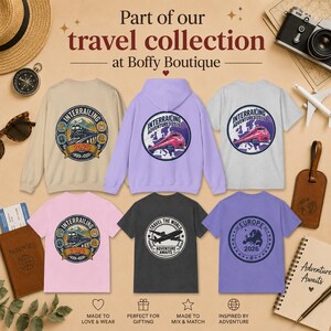 May include: A collection of six garments including sweatshirts and t-shirts in beige, lavender, gray, pink, charcoal, and purple. Each features a circular graphic with travel-themed designs like trains, airplanes, and maps with the text Part of our travel collection at Boffy Boutique.