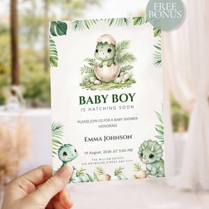 May include: A rectangular baby shower invitation card featuring a green dinosaur hatching from an egg, surrounded by tropical palm leaves. The text reads: BABY BOY IS HATCHING SOON, PLEASE JOIN US FOR A BABY SHOWER HONORING EMMA JOHNSON, 19 AUGUST, 2026 AT 3:00 PM, THE WILLOW ESTATE 125 ANYWHERE STREET ANY CITY.